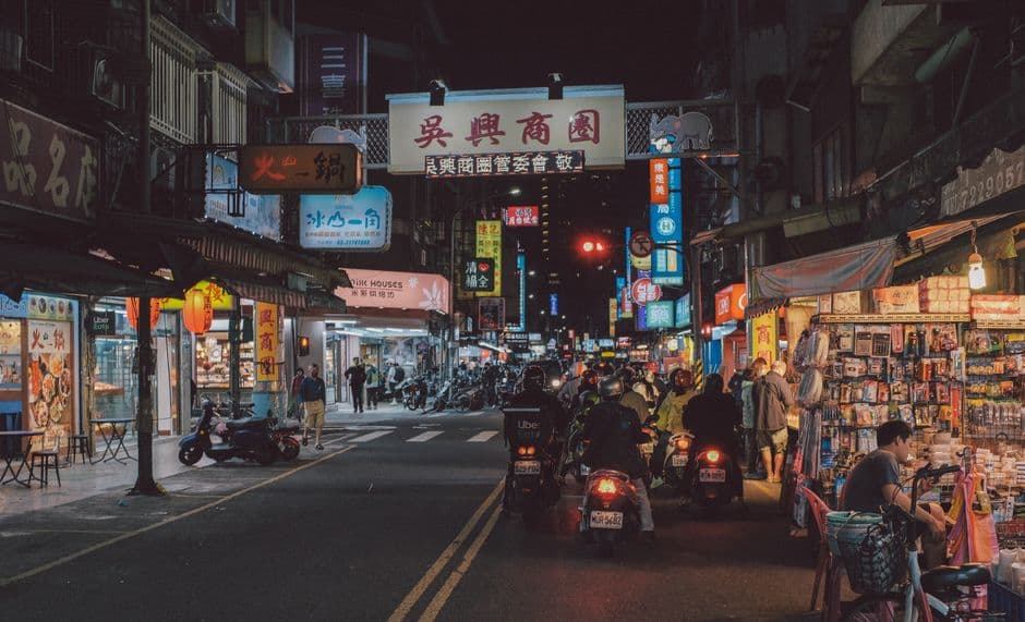 Stray dog sleeping under scooters night market Taiwan street